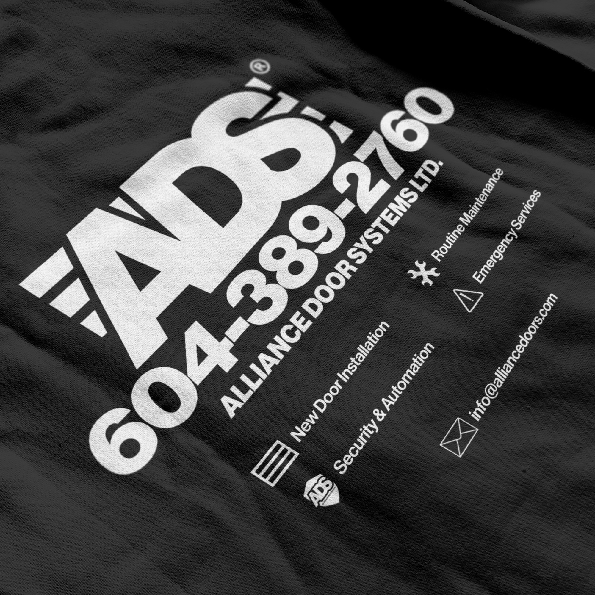 Close-up of a large white ADS print on black fabric listing services and contact details