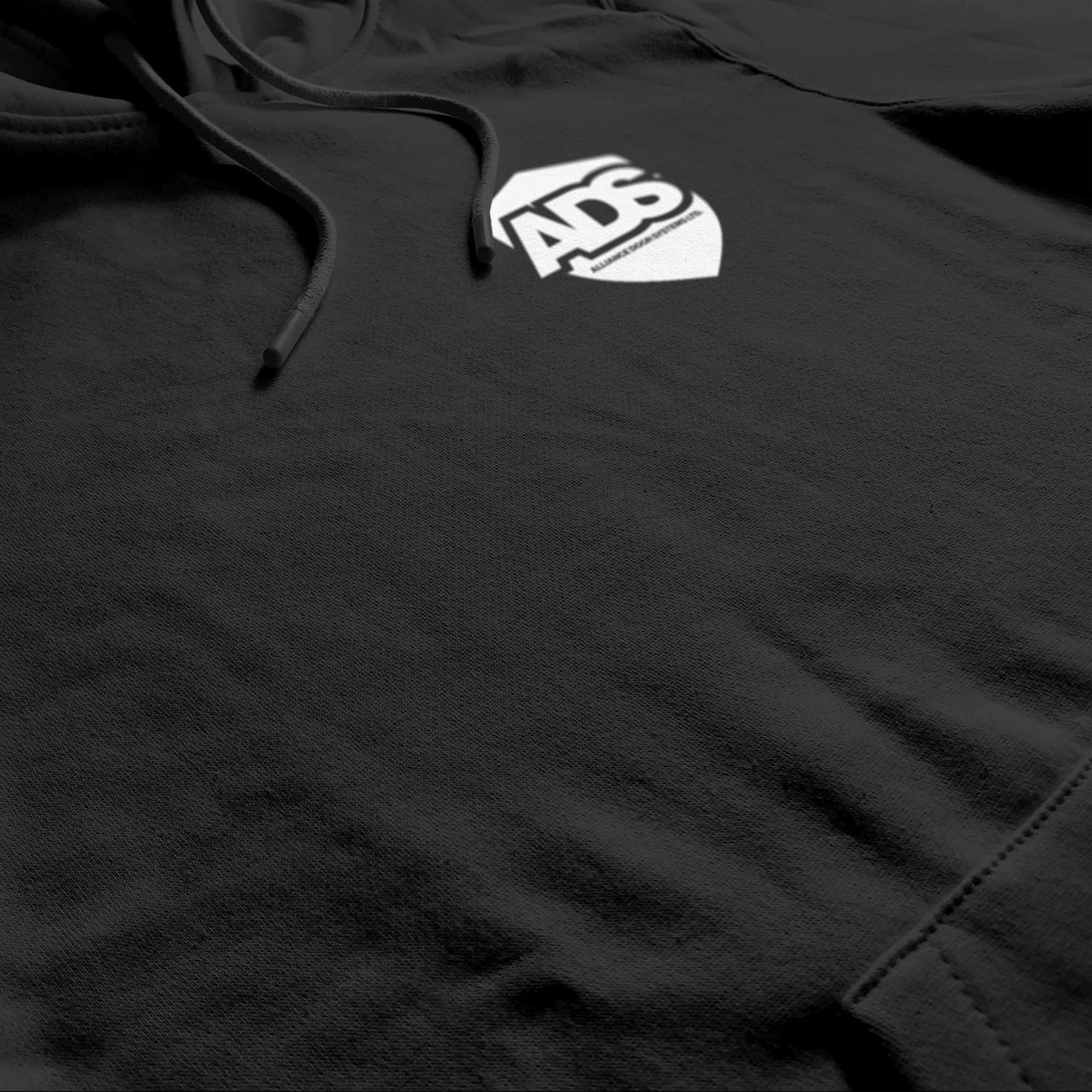 Close-up of the white ADS shield print on black hoodie fabric